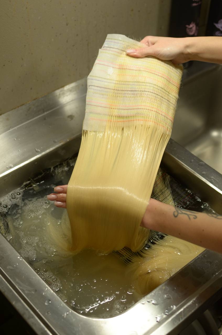 Gentle wash — hair extensions being washed by hand in the factory sink